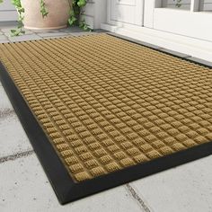 a door mat on the outside of a house with potted plants in the background