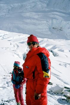 a man and child standing on top of a snow covered slope