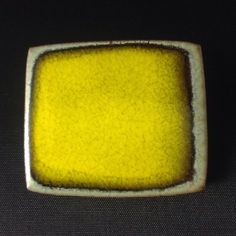 a yellow square shaped object sitting on top of a black surface with white trim around the edges