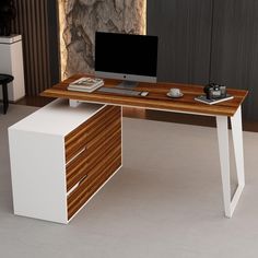 a computer desk with a monitor and keyboard on it in front of a stone wall