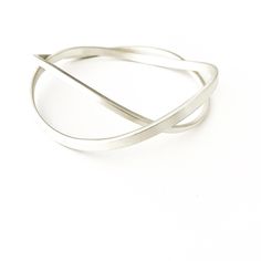 This solid sterling silver curved double interlinked bangle set sits beautifully on the hand and as it moves around creates interesting shapes. Each bangle has a matt/brushed finish with a square edge and are two different thicknesses which makes the design unique. This design is perfect to wear everyday. Metal: Solid Sterling Silver Width Widest bangle: 0.4 cm  Width: Narrower bangle: 0.25 cm Thickness: Widest bangle: 0.2 cm Thickness: Narrower bangle: 0.25 cm Profile: Square This listing is fo Modern Twist Sterling Silver Bracelet, Modern Twist Flexible Bangle As Gift, Modern Silver Flexible Bangle, Sterling Silver Bangle With A Modern Twist, Modern Twist Sterling Silver Bangle Bracelet, Sterling Silver Bracelet With A Modern Twist, Silver Bangle With A Modern Twist, Modern Twist Silver Bracelets, Modern Bangle