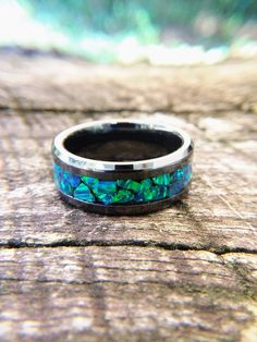 "This beautiful, black ceramic ring features large chunks of blue-green Peacock opal that have been thoughtfully arranged, one at a time, around the ring. The colors in this fire opal are hard to describe so I have included several pictures of the ring in both sunlight and shade. As the light hits the opal at different angles, the colors shift and change making this an eye catching piece of wearable art. This ring can be made in US sizes 6 to 14 including half sizes (but not 14.5). The ring pict Black Opal Round Jewelry, Green Peacock, Ceramic Ring, Black Ring, Ceramic Rings, Peacock Green, Ring Black, Black Ceramic, Black Rings