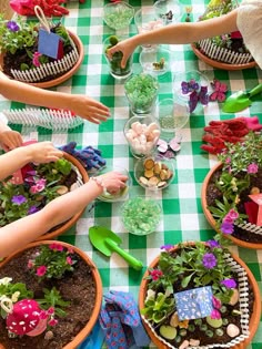 several people are sitting at a table with potted plants and gardening tools on it