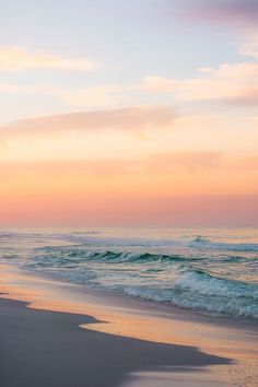 two people walking on the beach at sunset