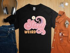 Embrace your unique personality with this 'Stay Weird' graphic tee! Made for those who celebrate their quirks, this shirt is a fun addition to any casual wardrobe. Its comfortable fit and bold design make a statement that's as individual as you are. Perfect for everyday wear, it keeps the positive vibes going whether you're out with friends or just lounging at home. Add a touch of the extraordinary to your style with this unisex fashion top, and enjoy being wonderfully weird. Quirky Girl, Stay Weird, Shirt Stays, Statement Shirt, Fashion Top, Bold Design, Top Casual, Casual Wardrobe, Unisex Fashion