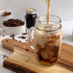 iced coffee being poured into a mason jar on top of a cutting board with chocolate chips