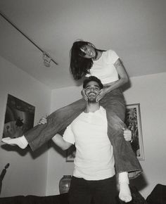 a man carrying a woman on his back in the living room while she holds her