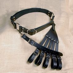 a black leather belt with spikes attached to it on a white cloth covered tablecloth