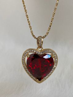 The Ruby Heart Necklace is enchanting! This heart necklace came straight out from a rom-com! It features a large heart-shaped cubic zirconia ruby crystal hugged in a micro pave frame and suspended on a dainty twisted box chain necklace. She takes all other ruby heart necklaces off the scene! Available in 24K gold or rhodium plating over steel Patent plating & sealant technology to ensure durability and long lasting wear Made in Los Angeles, CA | Nickel & Lead Free Luxury Red Amulet Necklace, Square Ruby Necklace, Luxury Red Choker For Gift, Gold Double Heart Gemstone Necklace, Cubic Zirconia Heart Necklace With Gemstone For Valentine's Day, Heart Necklace With Cubic Zirconia For Valentine's Day, Cubic Zirconia Heart Necklace With Gemstone, Valentine's Day Heart Necklace With Cubic Zirconia Gemstone, Valentine's Day Cubic Zirconia Heart Necklace