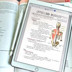 an ipad displaying the upper limb muscles on it's screen and in front of some books