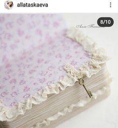 an open book with a key hanging from it's cover and lace on the edge