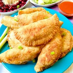 some food is on a blue plate with other foods in bowls and sauces behind it