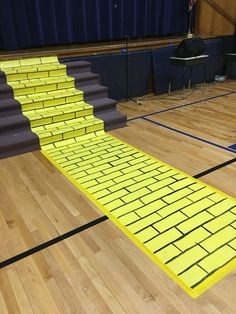 a set of stairs made out of yellow brick blocks on a wooden floor in front of a blue curtain