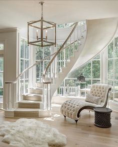 an elegant staircase in the middle of a living room with white furniture and rugs on the floor