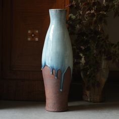 a blue and brown vase sitting next to a potted plant