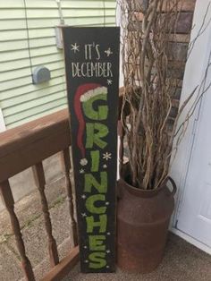 a wooden sign that says it's december and green christmas stockings on the front porch