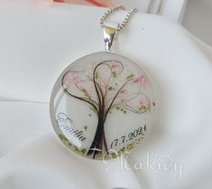 a glass pendant with a tree on it and the words family written in pink flowers