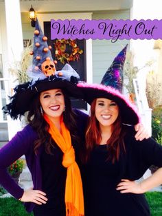 two women wearing witches hats and scarves pose for a photo in front of a house