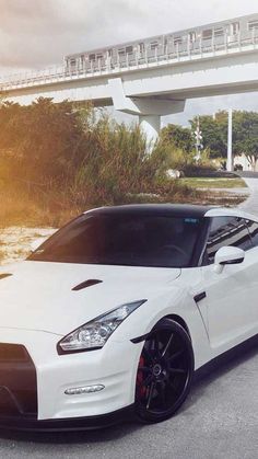 a white sports car parked in front of a bridge