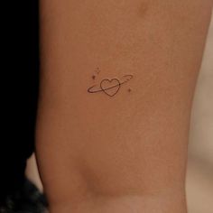 a small tattoo on the back of a woman's left arm, with an intertwined heart and stars