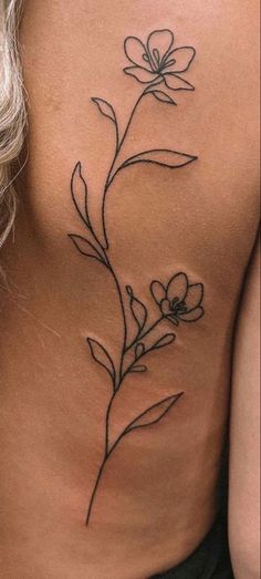 a woman's back with a flower tattoo on her left side ribcage