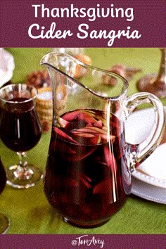 a pitcher filled with liquid sitting on top of a table next to plates and glasses