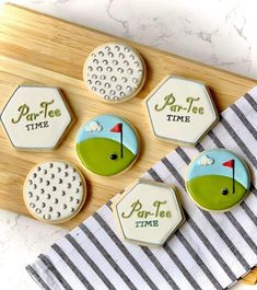 decorated cookies with golf designs are on a cutting board next to a white and black striped towel