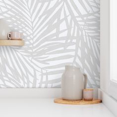 a white vase sitting on top of a counter next to a cup and saucer