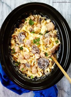 a black crock pot filled with pasta and meat