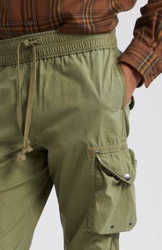 Relaxed-fit cargo pants are equipped with eight pockets, featuring grommets, rivets and snaps throughout for an authentic utilitarian feel. Cut from lightweight cotton poplin, these pants feature a pinched-seam technique before the garment-dye and wash process, revealing subtle variations in color after the pinching is released. 31" inseam; 14" leg opening; 12" front rise; 16" back rise (size Medium) Elastic/drawstring waist Front slant pockets; cargo bellows snap-flap pockets with internal draw Combat Style Cotton Bottoms With Pockets, Cotton Cargo Combat Bottoms, Combat Cotton Pants With Cargo Pockets, Cotton Combat Cargo Bottoms, Combat Cotton Bottoms With Multiple Pockets, Cotton Combat Bottoms With Multiple Pockets, Military Cotton Cargo Pants With Flap Pockets, Military Style Cotton Cargo Pants With Flap Pockets, Military Cotton Bottoms With Cargo Pockets