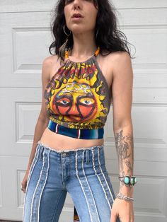 a woman in jeans and a crop top is standing by a garage door with her hand on her hip