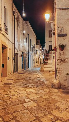 an empty street at night with some lights on and no people in the alleyway