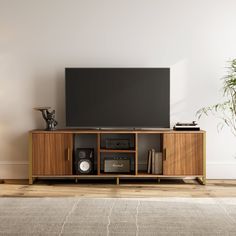 a flat screen tv sitting on top of a wooden entertainment center next to a potted plant