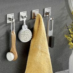 a towel hanging on the wall next to two toothbrushes and a brush in a holder