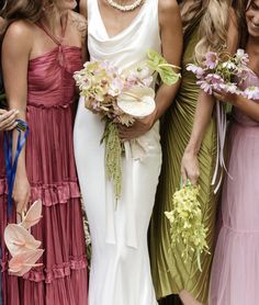 a group of women standing next to each other in dresses and holding bouquets with flowers on them