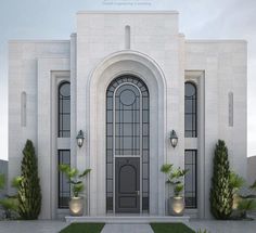 a large white building with an arched door and two planters on the front lawn