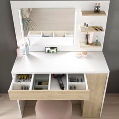 a white desk with drawers underneath it and a mirror on the wall behind it,