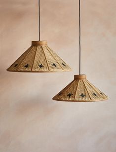 two lamps hanging from the ceiling in front of a beige wall with black stars on it