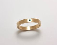 A sparkling 1.75 mm diamond cut A grade emerald flush set in a 14k gold 3 mm band in this striking minimalist ring. A flush setting gives an added amount of security to the stone. The ring can be worn by itself or as an accompaniment to another ring. If you would like an emerald of a different grade or a ring size larger than those listed, please request an estimate.  This ring would make a beautiful engagement or wedding ring. Or a "just because" ring!This is a natural emerald with no enhanceme Modern Stackable Emerald Ring For Anniversary, Minimalist Emerald Diamond Ring For May Birthstone, Minimalist Emerald Birthstone Ring With Bezel Setting, Modern Diamond Ring For May Birthstone, Modern 14k Gold Emerald Wedding Ring, Modern May Birthstone Diamond Ring, Modern Birthstone Ring With Single Diamond In Round Band, 14k Gold Emerald Ring With Single Diamond For Promise, Modern Birthstone Ring With Single Diamond