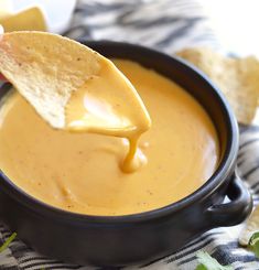 a tortilla chip being dipped into a bowl of quesadilla dip