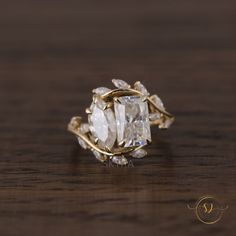 a close up of a ring on a wooden surface with the center stone surrounded by leaves