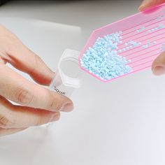 two hands holding a pink and white comb with blue sprinkles on it