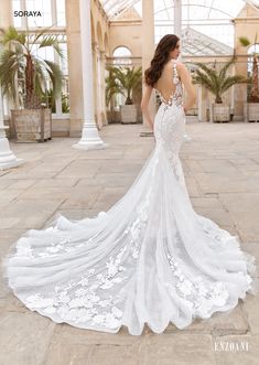 a woman in a white wedding dress standing on a stone floor with her back to the camera