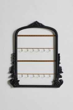 a mirror that is hanging on the wall next to a rack with earring hooks