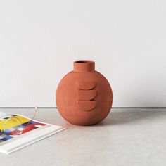 a clay vase sitting on top of a table next to a magazine