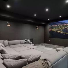 a large gray couch sitting in front of a projector screen with city lights on it