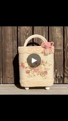 a white basket with pink flowers on it sitting next to a wooden fence and holding a video game controller