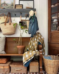 a wooden bench with baskets on it next to a wall mounted coat rack and other items