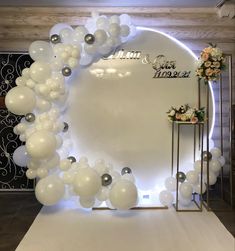 balloons and flowers are on display in front of a white backdrop for a wedding ceremony