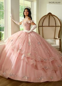 This dress is meant to make any young lady feel like a princess from a fairy tale; it is whimsical and romantic. This event will be exceptionally memorable thanks to the enchanting look created by a glitter tulle fabric and a cold shoulder neckline. The piece has an extra dose of girlish charm from the layered ruffles and an extra sparkle from the beading and applique details. The lace-up back of this dress is a striking detail. The last bit? The dreamlike ensemble is completed with matching glo Quinceanera Dresses Dusty Rose, Quincera Dresses Pink, Mom Dress For Quinceanera, Quince Dress With Gloves, Salmon Quinceanera Dresses, Quince Dresses Colors, Quinceañera Dress Ideas, Big Pink Quinceanera Dresses, Quinceanera Dresses With Gloves